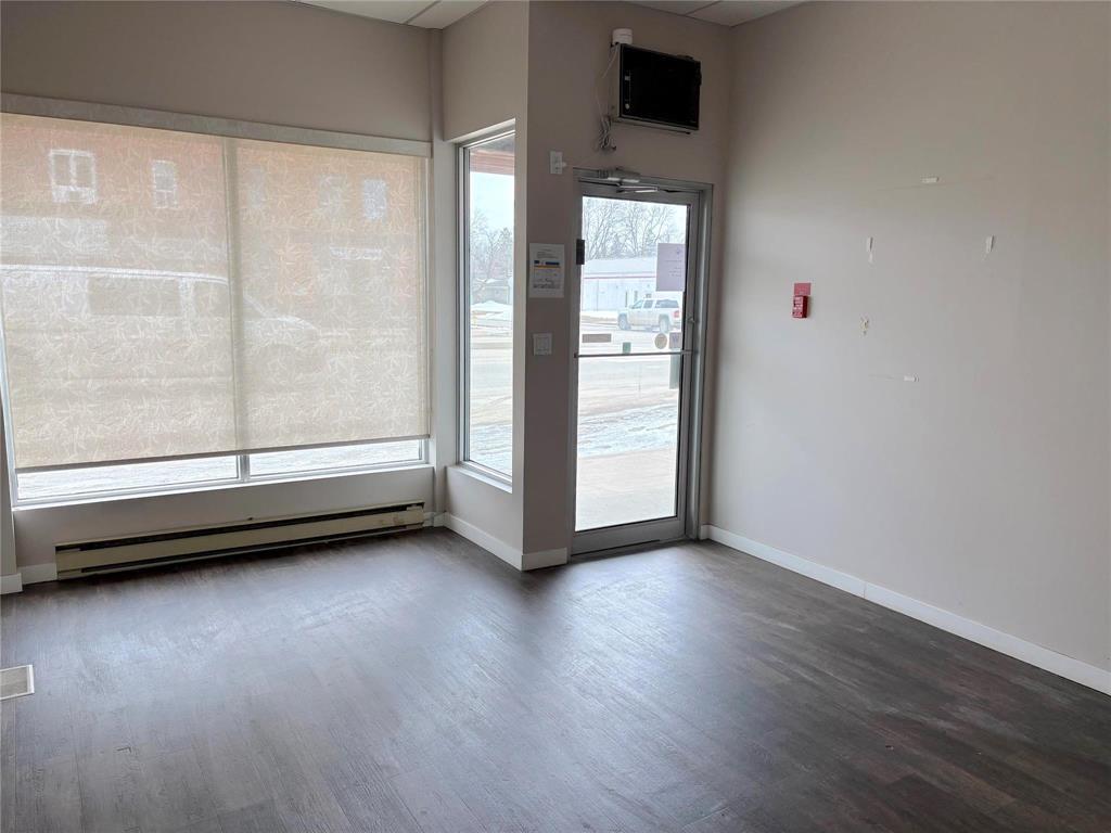 A room with a wooden floor and a door leading to a parking lot.