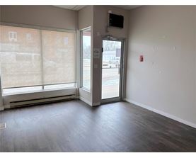 A room with a wooden floor and a door leading to a parking lot.