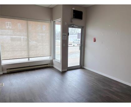 A room with a wooden floor and a door leading to a parking lot.