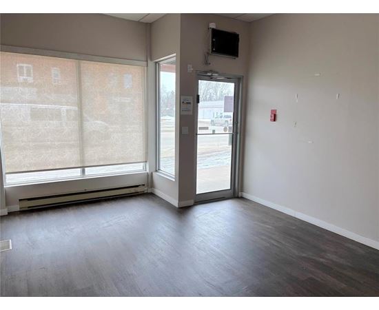 A room with a wooden floor and a door leading to a parking lot.