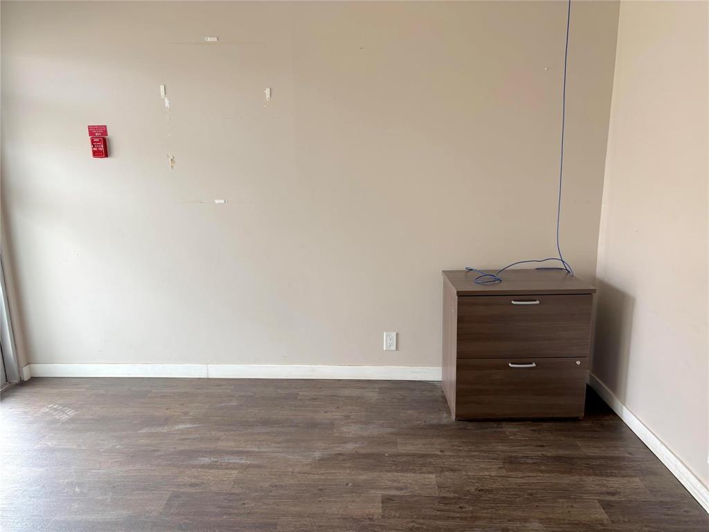 A room with a brown drawer cabinet and a red fire alarm on the wall.