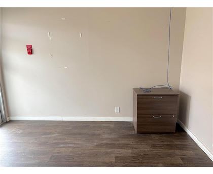 A room with a brown drawer cabinet and a red fire alarm on the wall.