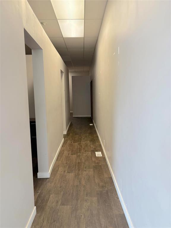 A long, narrow hallway with wood flooring and white walls.