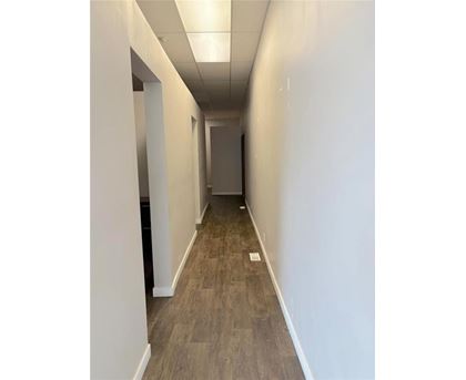 A long, narrow hallway with wood flooring and white walls.