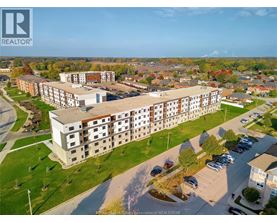 An aerial view of a large apartment complex with a parking lot in front.