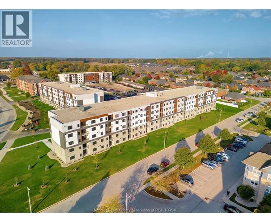 An aerial view of a large apartment complex with a parking lot in front.