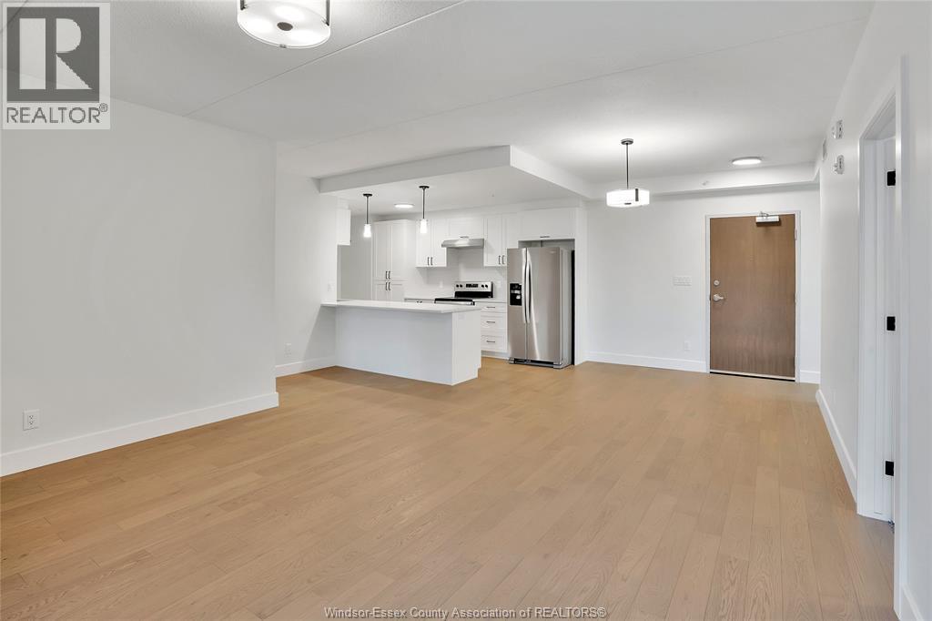 A spacious, empty room with wooden flooring and white walls.