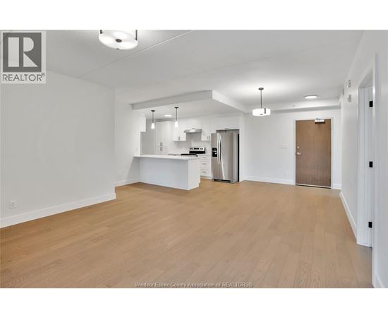 A spacious, empty room with wooden flooring and white walls.