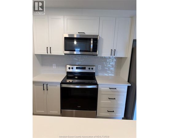 A kitchen with white cabinets and a black stove top oven.