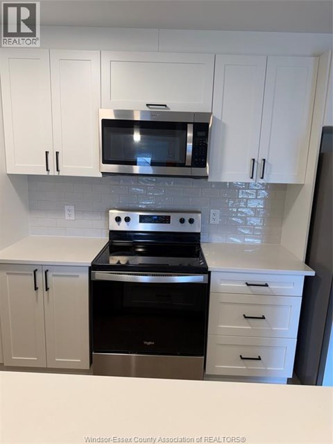 A kitchen with white cabinets and a black stove top oven.
