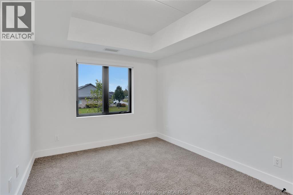 A white room with a carpeted floor and a window showing a view of a house and trees.