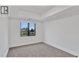 A white room with a carpeted floor and a window showing a view of a house and trees.