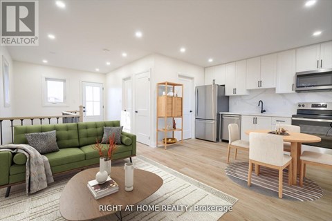 A well-lit, modern kitchen and living room with a green sofa and wooden furniture.