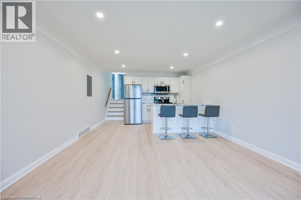 A spacious room with a bar area and a staircase leading to the upper floor.