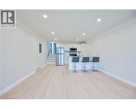 A spacious room with a bar area and a staircase leading to the upper floor.