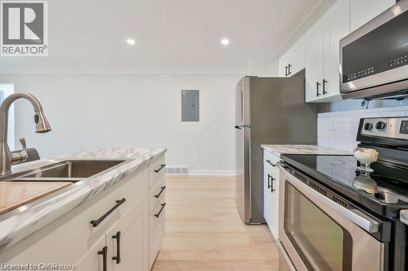 A modern kitchen with stainless steel appliances and wooden flooring.
