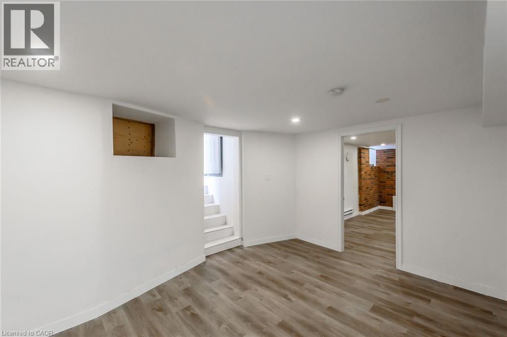 A spacious room with wooden flooring and white walls.