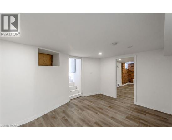 A spacious room with wooden flooring and white walls.