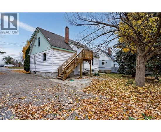 A house with a gravel driveway and a tree with yellow leaves.