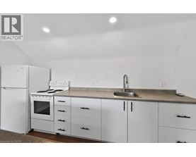 A white kitchen with a sink and a refrigerator.