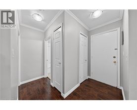 A white hallway with three doors and wood floors.