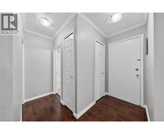 A white hallway with three doors and wood floors.