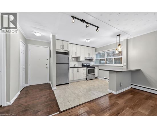 A well-lit kitchen with white cabinets and a wooden floor.