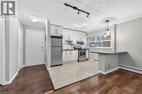 A well-lit kitchen with white cabinets and a wooden floor.