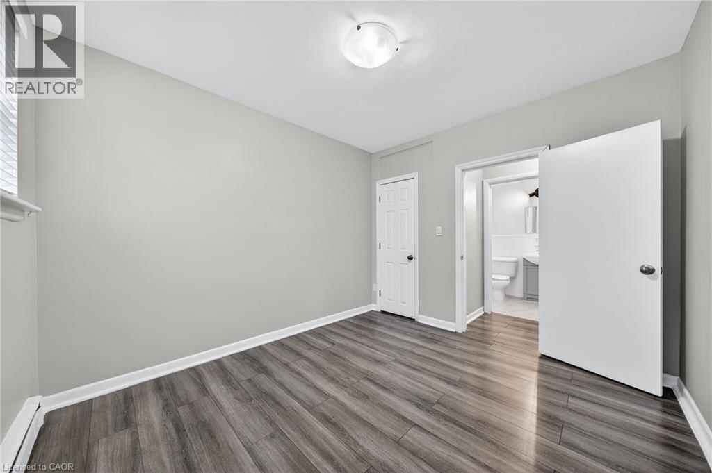 A spacious room with wood flooring and white walls.