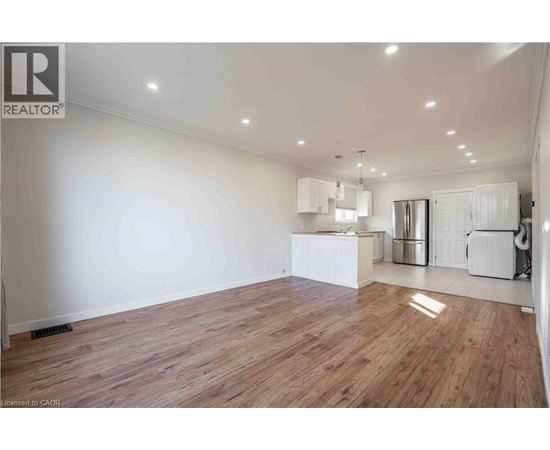 A spacious room with wooden flooring and white walls.