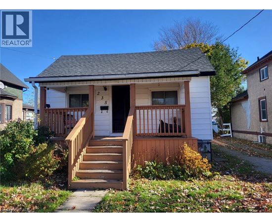 A small white house with a brown front porch.