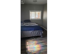 A bedroom with a bed and a window with blinds.