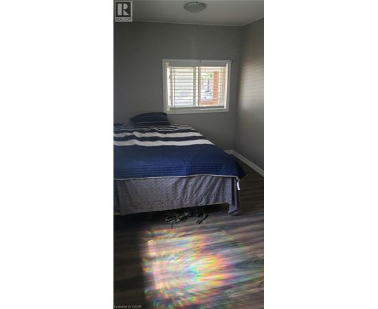 A bedroom with a bed and a window with blinds.