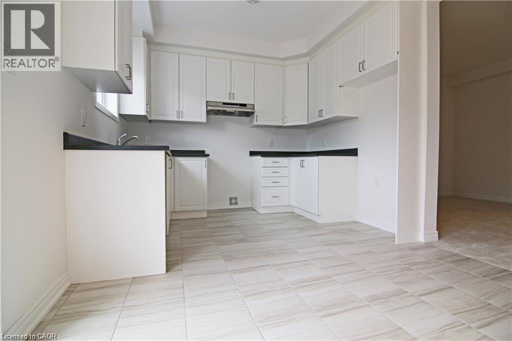 A kitchen with white cabinets and a black countertop.