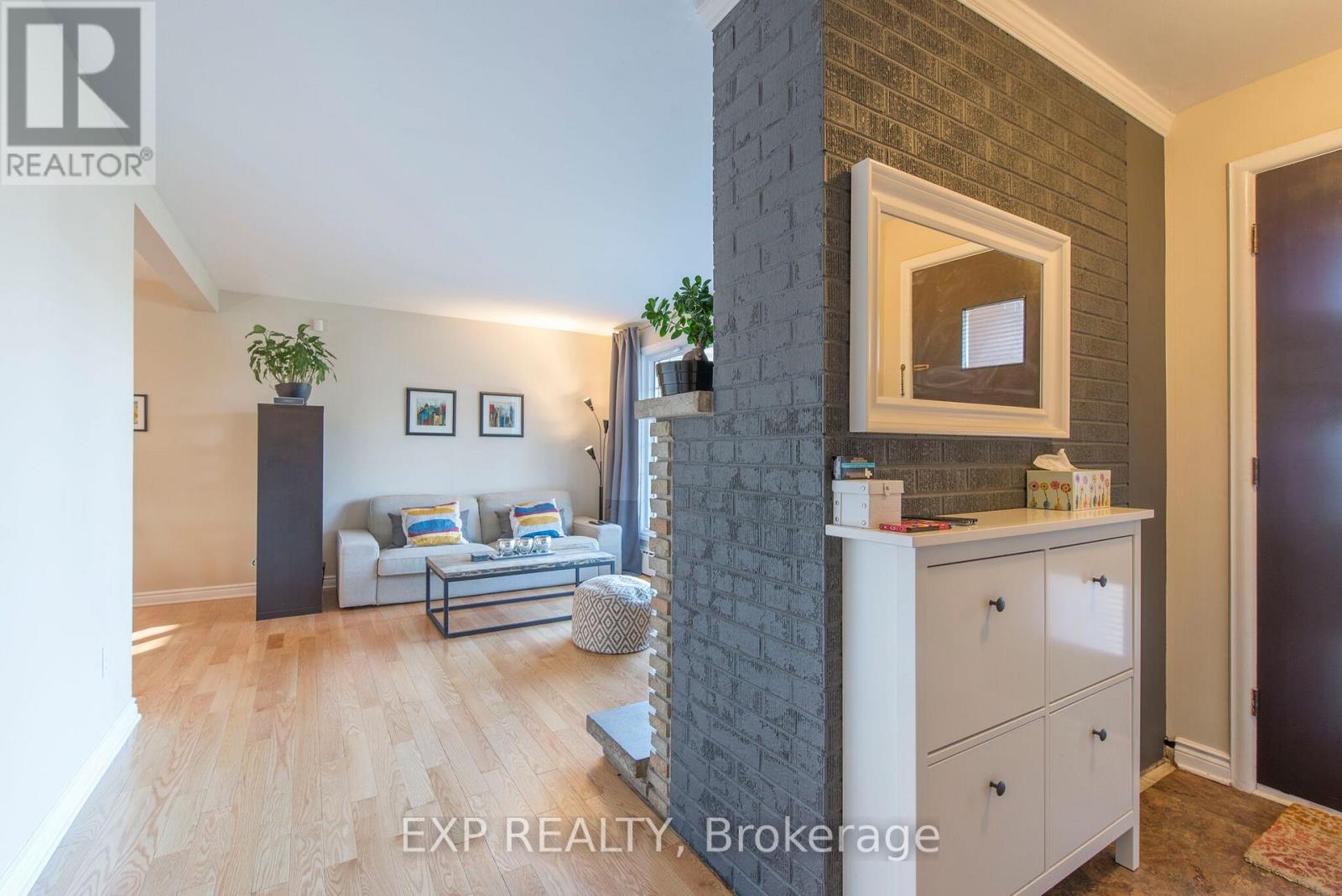 A living room with a grey brick wall and a white sofa.