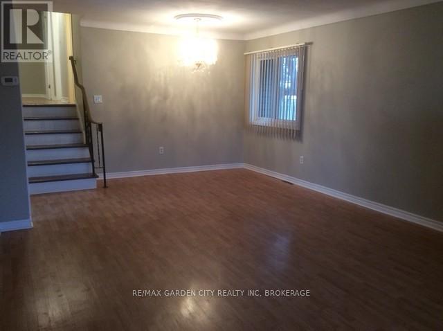 A room with wooden flooring and a window with blinds.