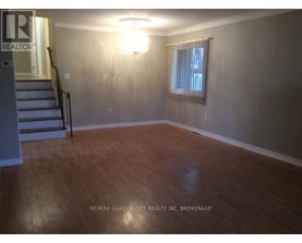A room with wooden flooring and a window with blinds.