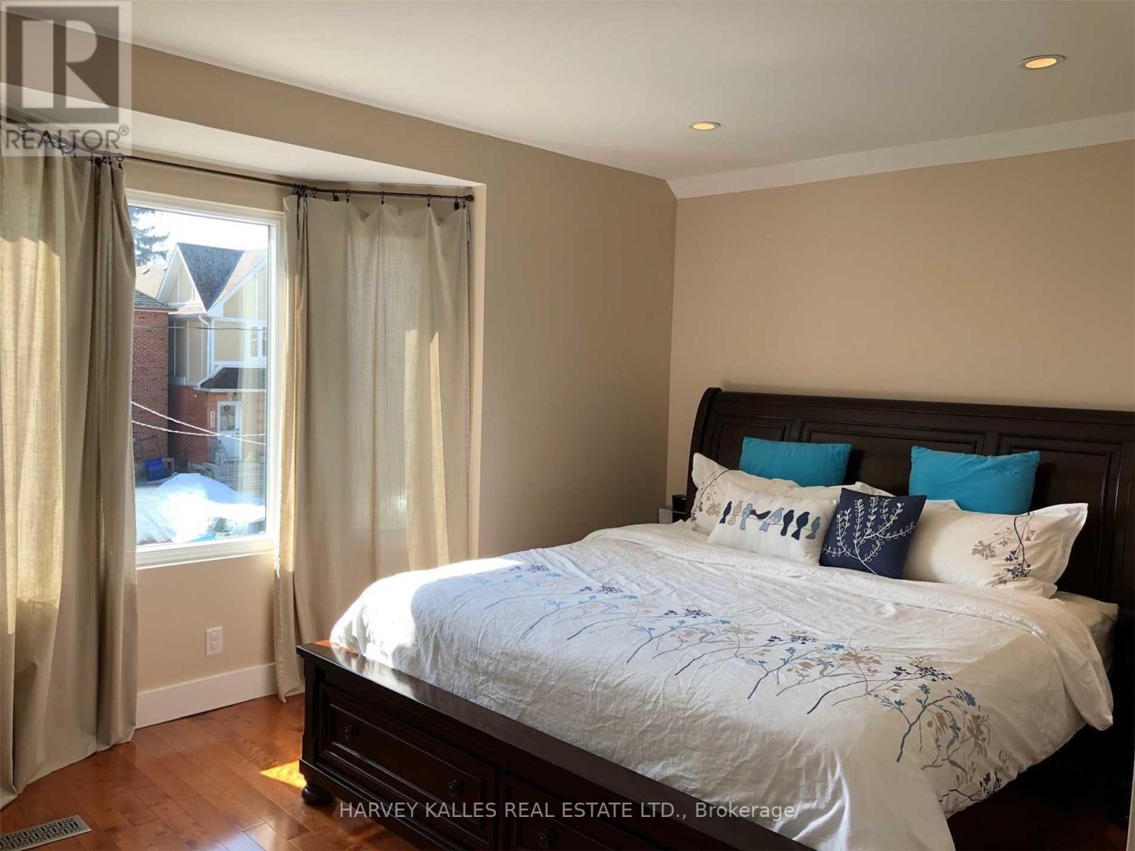 A bedroom with a large bed and a window with curtains.
