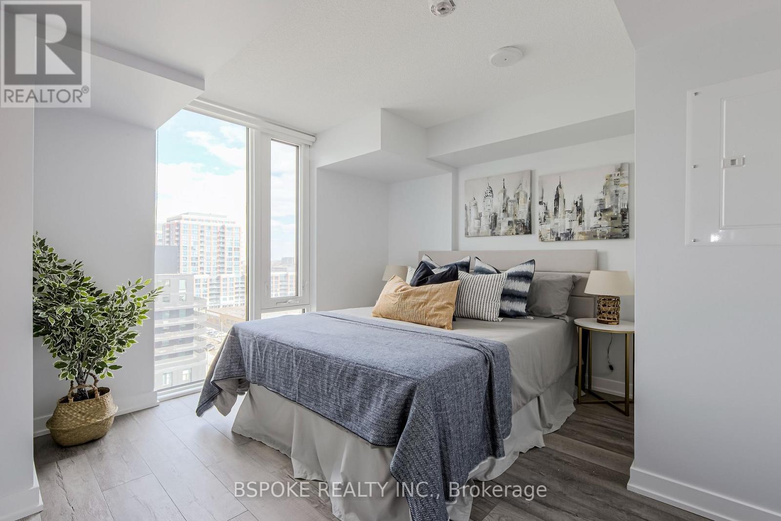 A bedroom with a bed, a potted plant, and pictures on the wall.