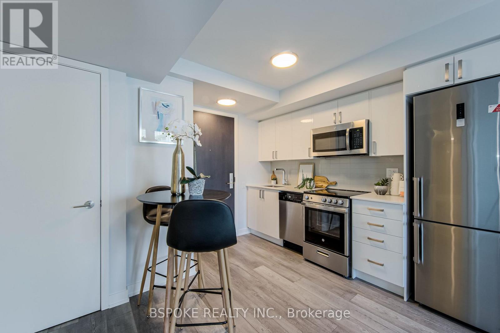 A modern kitchen with stainless steel appliances and a bar stool.
