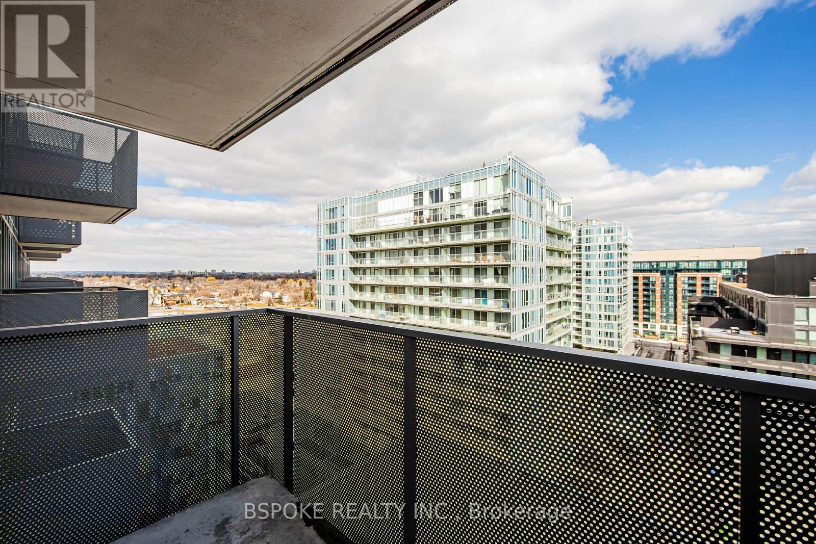 A modern building with a glass facade is seen from a balcony.