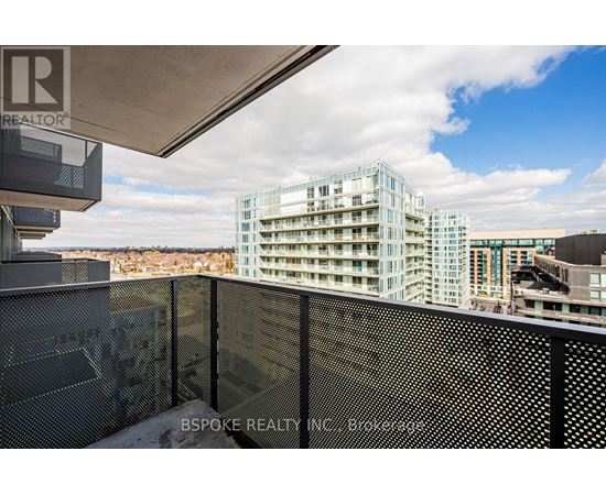 A modern building with a glass facade is seen from a balcony.