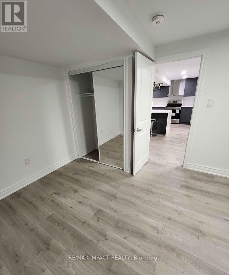 A room with a wooden floor and a doorway leading to a kitchen.