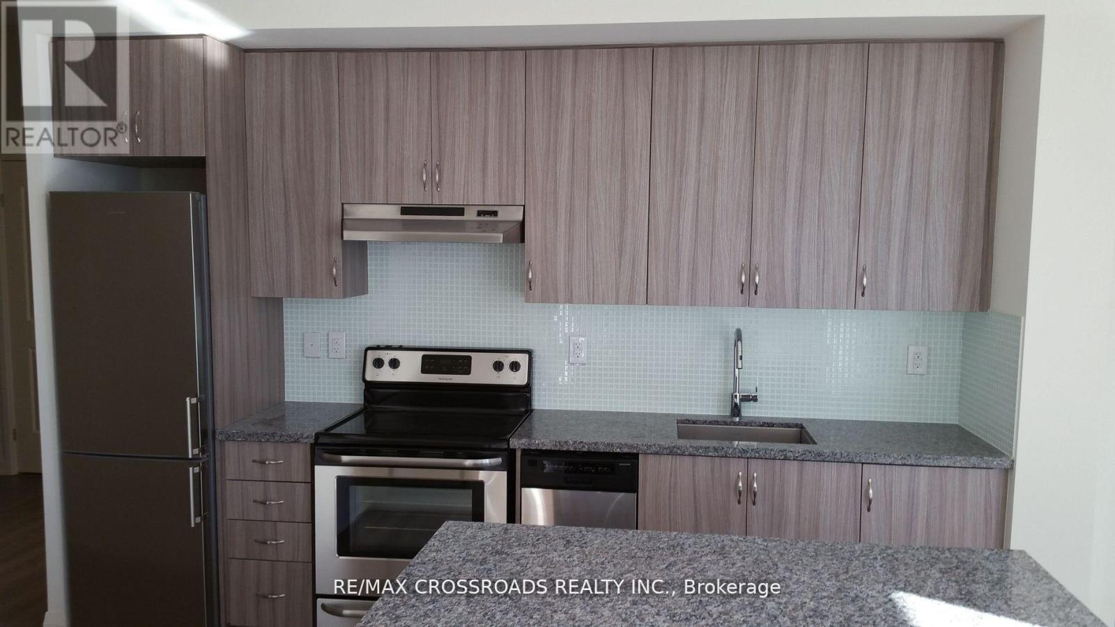 A kitchen with a refrigerator, oven, and sink.