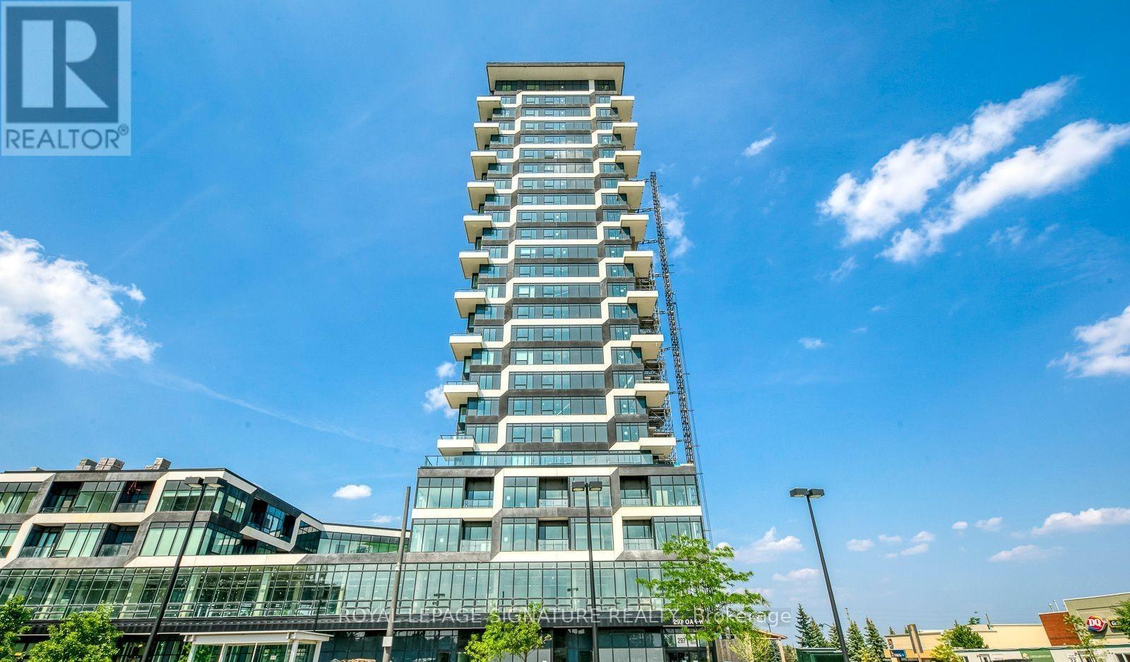 A tall building with a glass facade stands in front of a blue sky with clouds.