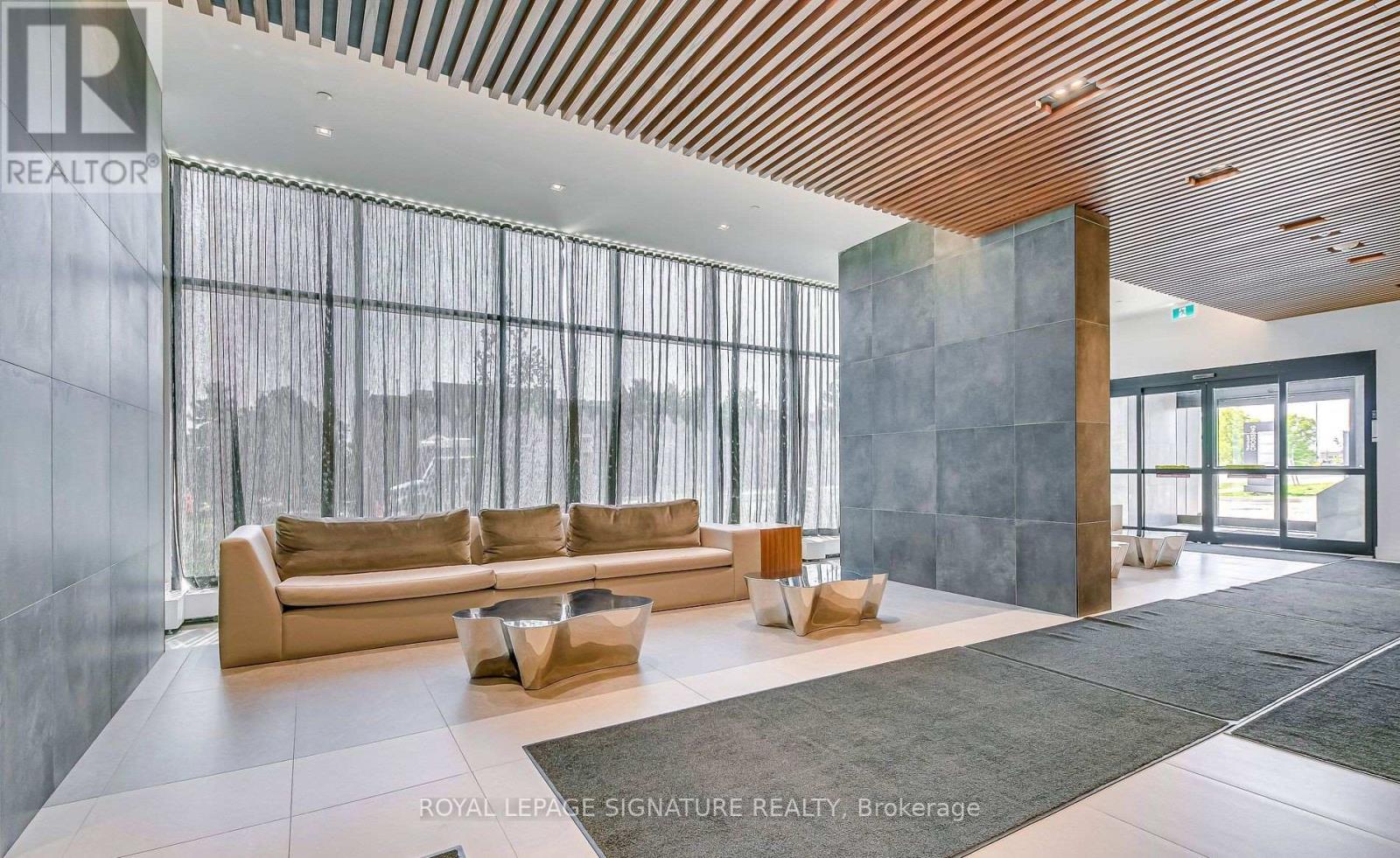 A spacious living room with a large couch and a wooden ceiling.