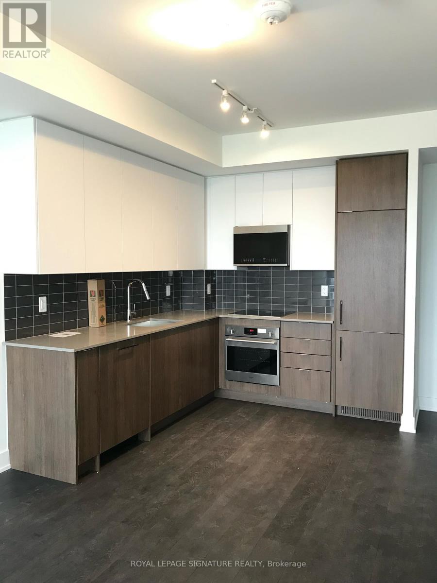 A modern kitchen with wooden cabinets and a black tile backsplash.