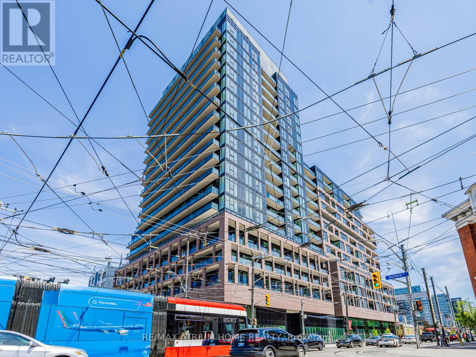 A tall building with many windows is under construction with a blue RE/MAX sign in the foreground.