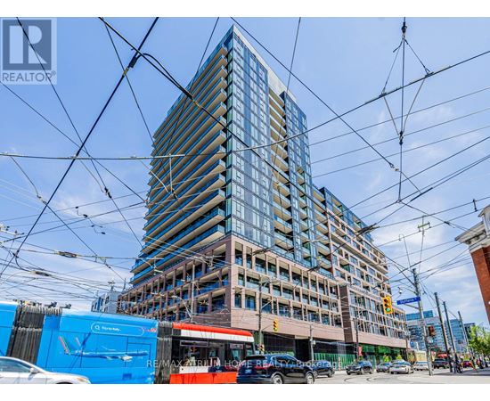 A tall building with many windows is under construction with a blue RE/MAX sign in the foreground.