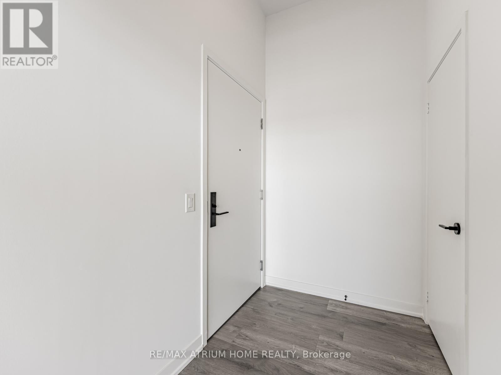 A white room with a door and a brokerage sign.